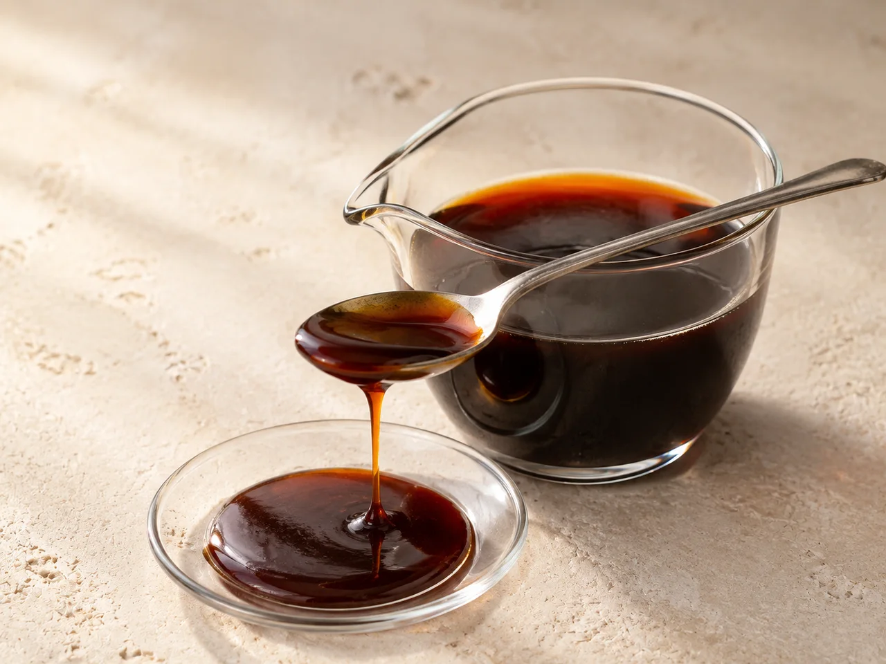 Dark date syrup in a glass vessel with a tasting spoon